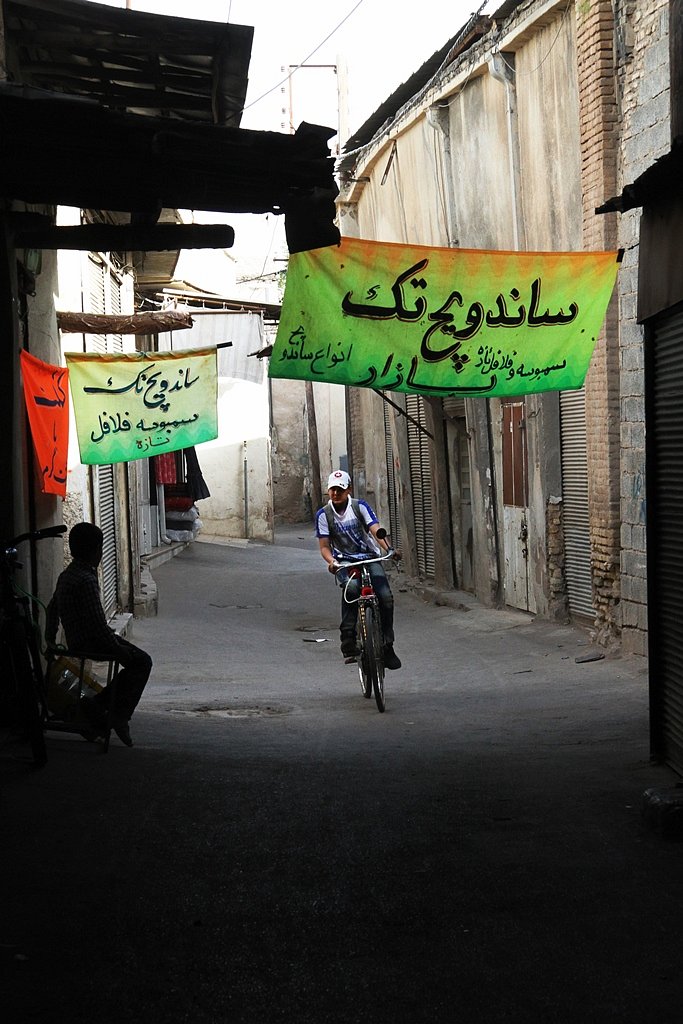 A boy is cycling in the alleys of the bazaar in Shiraz.